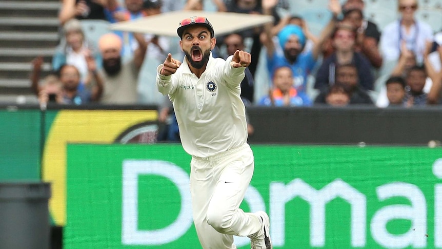 India captain Virat Kohli pulls a manic facial expression and points with both fingers while running in the field at the MCG.