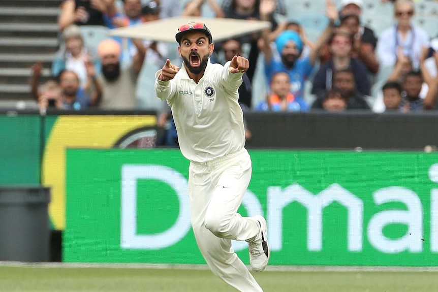 India captain Virat Kohli pulls a manic facial expression and points with both fingers while running in the field at the MCG.