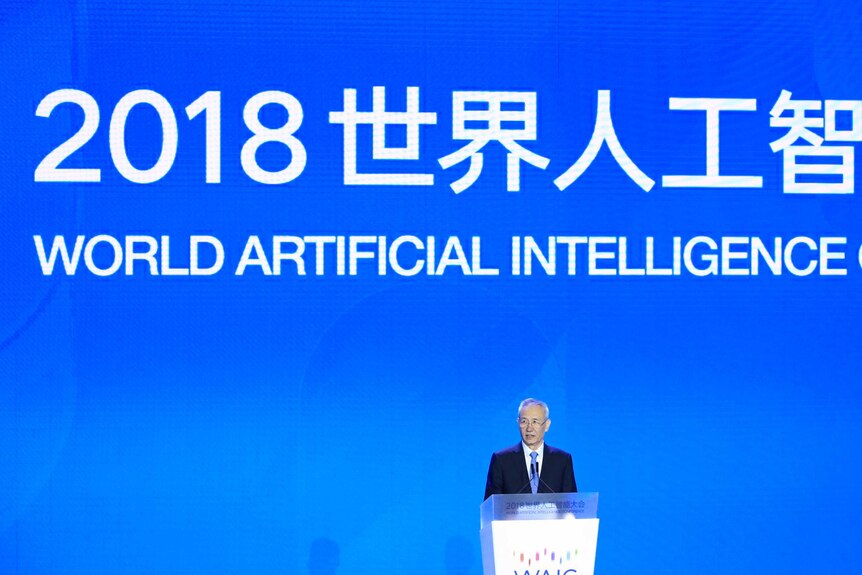 Liu He stands at a lectern with a big sign behind reading 2018 world artificial intelligence.