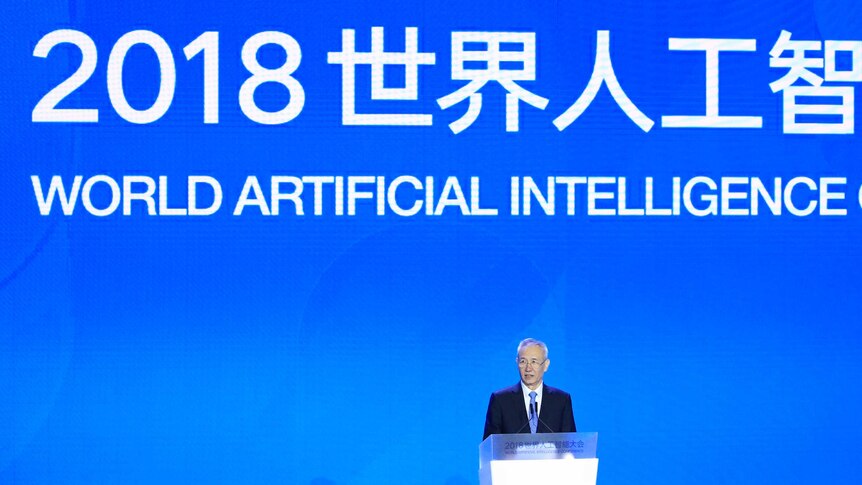 Liu He stands at a lectern with a big sign behind reading 2018 world artificial intelligence.