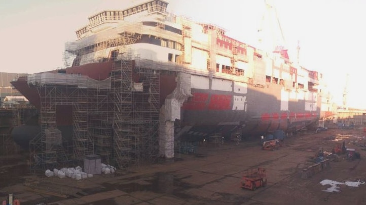 Large passenger ship under construction in a dry dock shipyard.