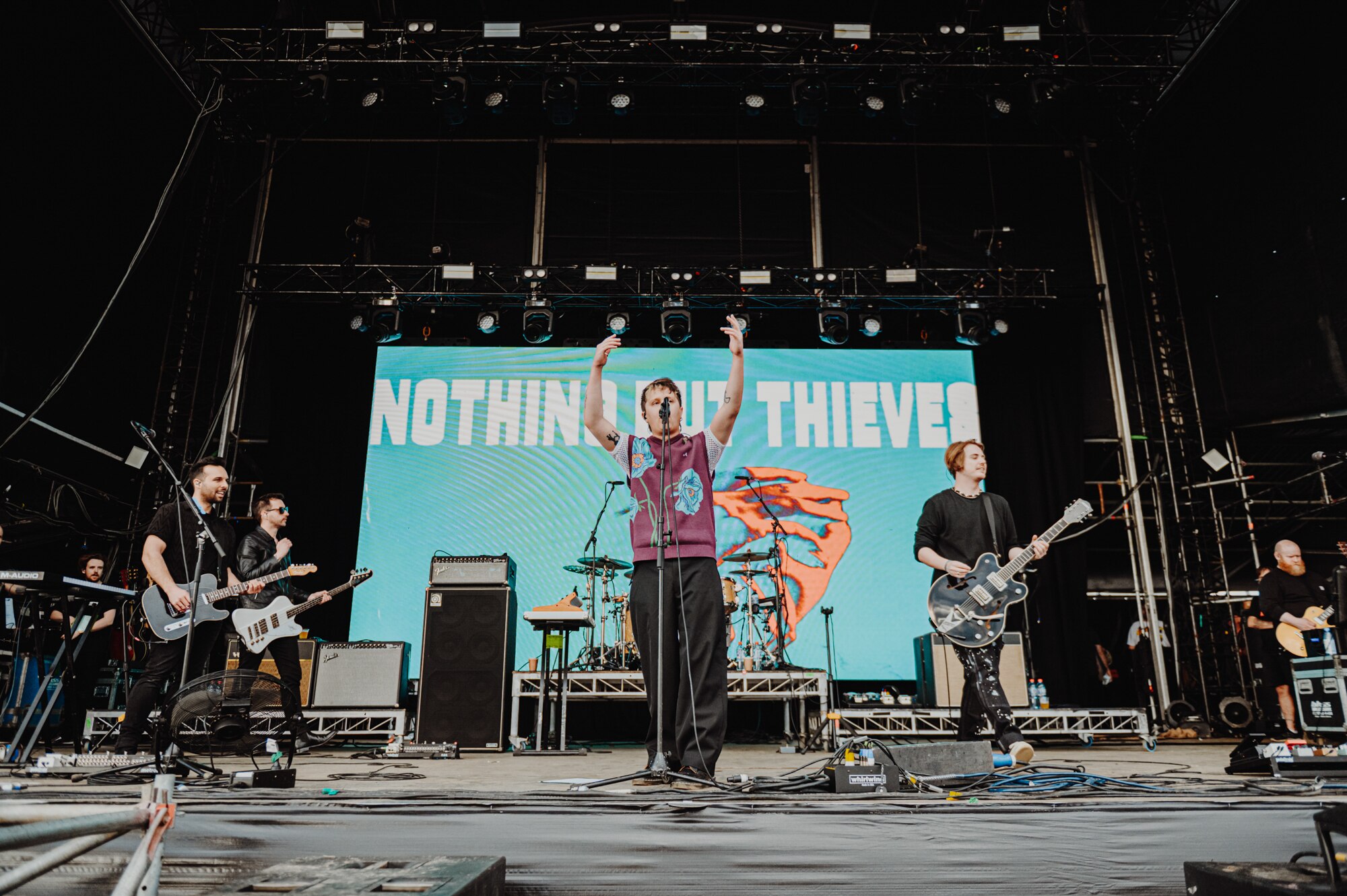 A band performs onstage at an outdoor concert.
