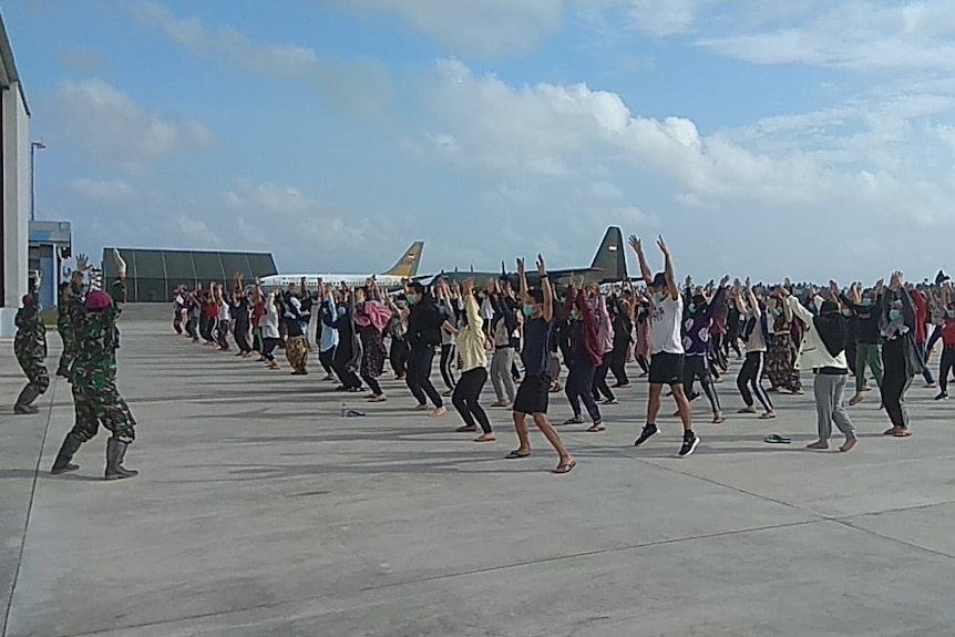 Evacuees and Indonesian military personnel doing morning aerobics.
