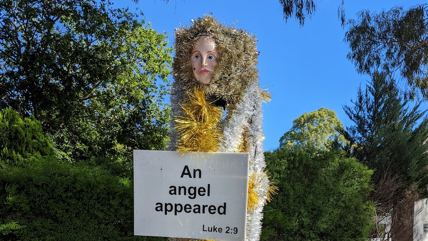 A tall figure covered in tinsel with a sign reading 'An angel appeared'