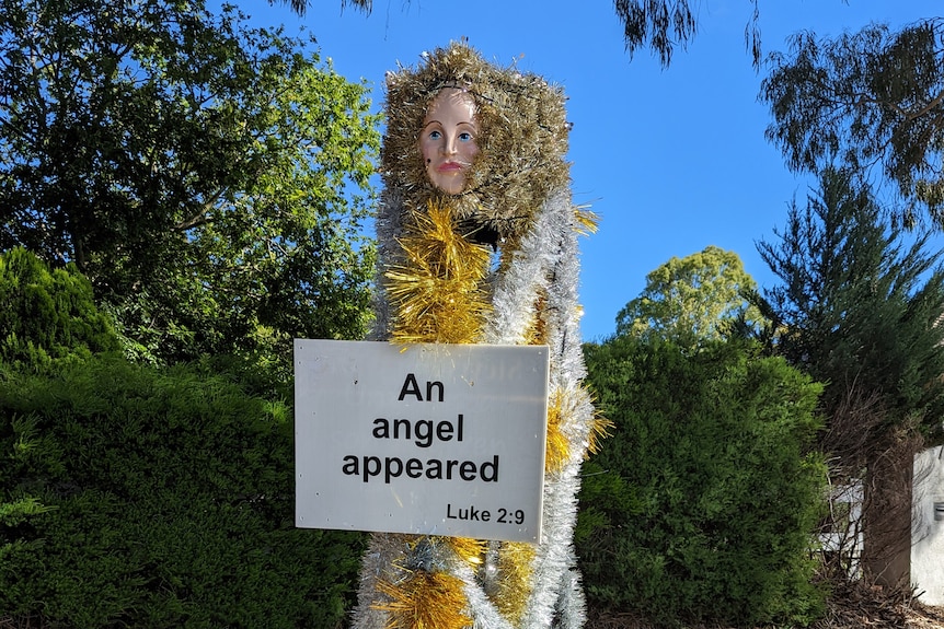 A tall figure covered in tinsel with a sign reading 'An angel appeared'
