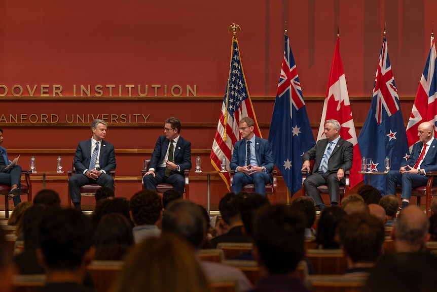 A row of men in suits sitting on a stage 