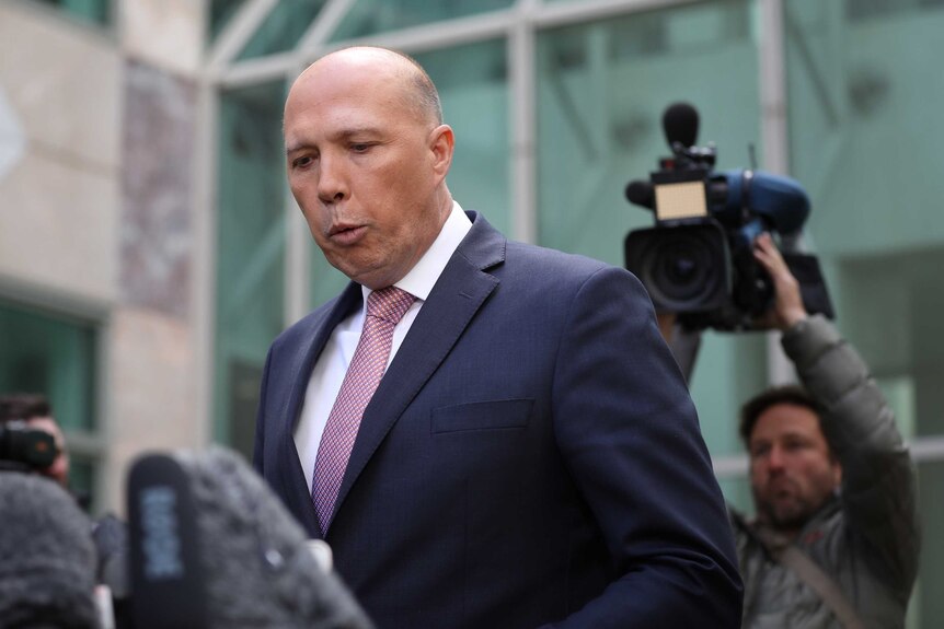 Peter Dutton purses his lips in front of television cameras