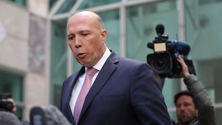 Peter Dutton purses his lips in front of television cameras