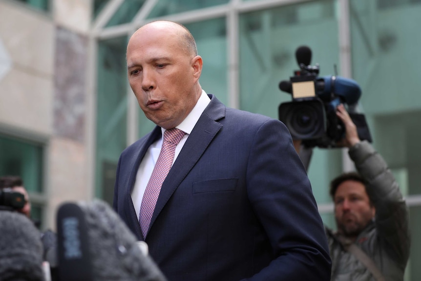 Peter Dutton purses his lips in front of television cameras