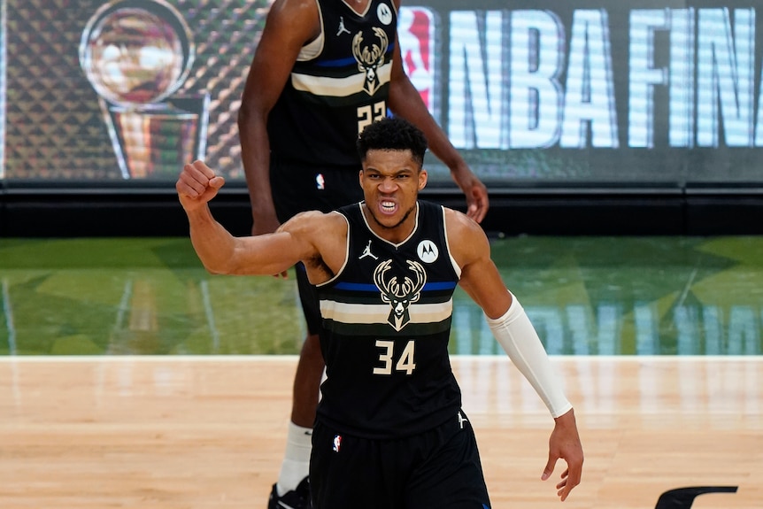 NBA player Giannis Antetokounmpo stands in mid-court clenching his fist in celebration during NBA Finals game 6