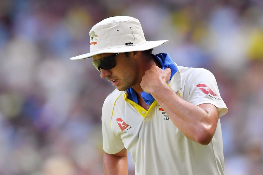 Pat Cummins tries to cool himself with a towel under his collar while fielding