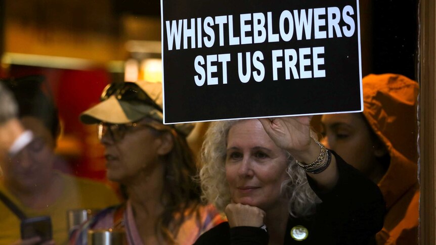 Protestor holds sign in support of whistleblower