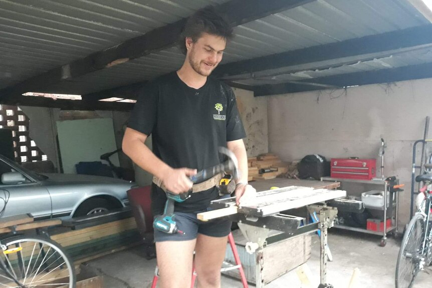 Luke Holliday in a garage using a hammer.