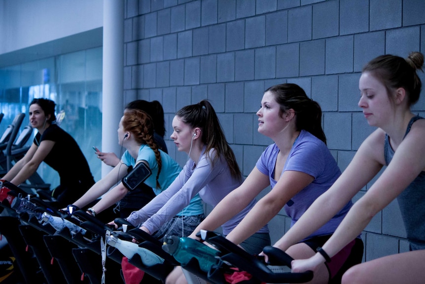 Women in a cycling or spin class at a fitness centre.