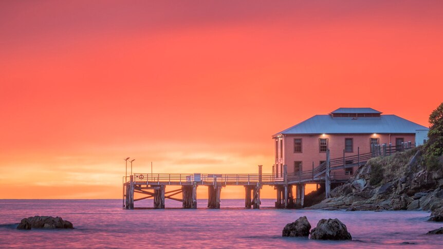 Tathra wharf pictured at sunset in story about encouraging tourists to visit regional Australia after natural disasters.