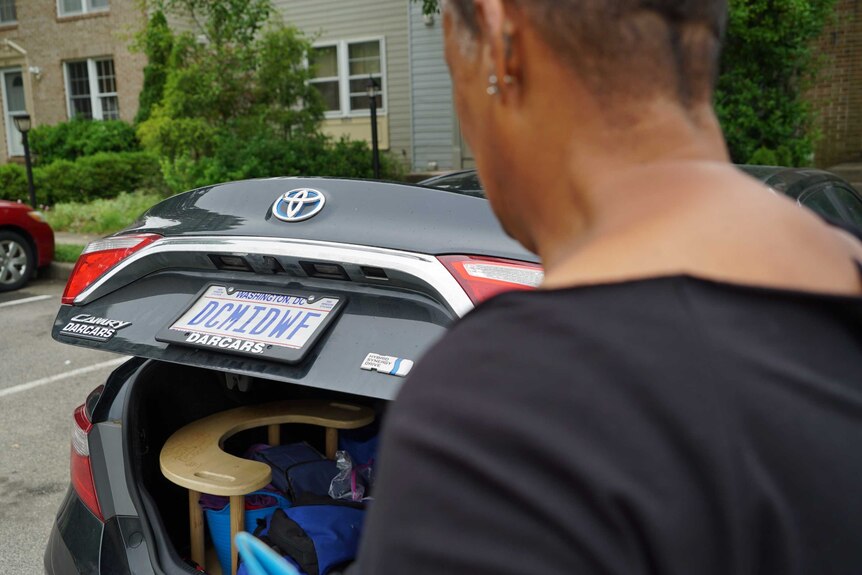 Midwife Claudia Booker approaches her car, the boot of which is full of birthing equipment.