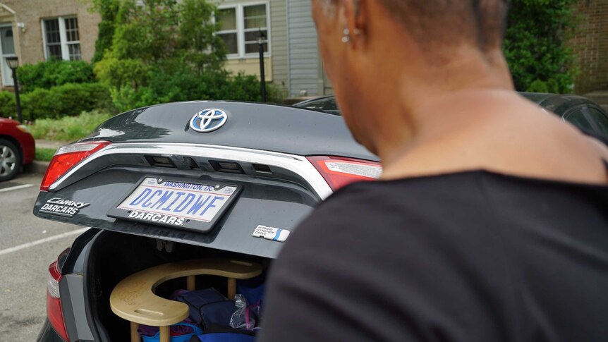 Midwife Claudia Booker approaches her car, the boot of which is full of birthing equipment.