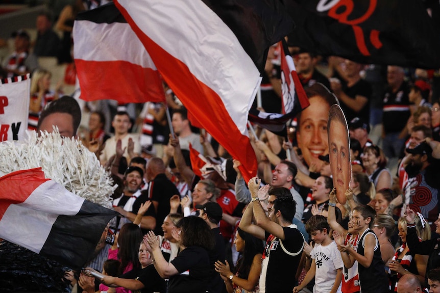 A crowd of St Kilda fans clap and yell.