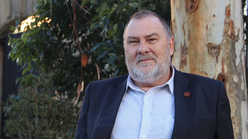 Tasmanian timber industry stalwart, Terry Edwards stands in front of a tree.