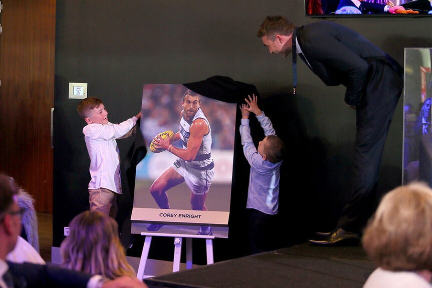 two children pull off material cover from a photograph of a AFL footballer