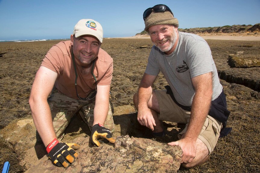 Dr Erich Fitzgerald and Yestin Griffiths crouched next to a boulder on the Victorian Surf Coast