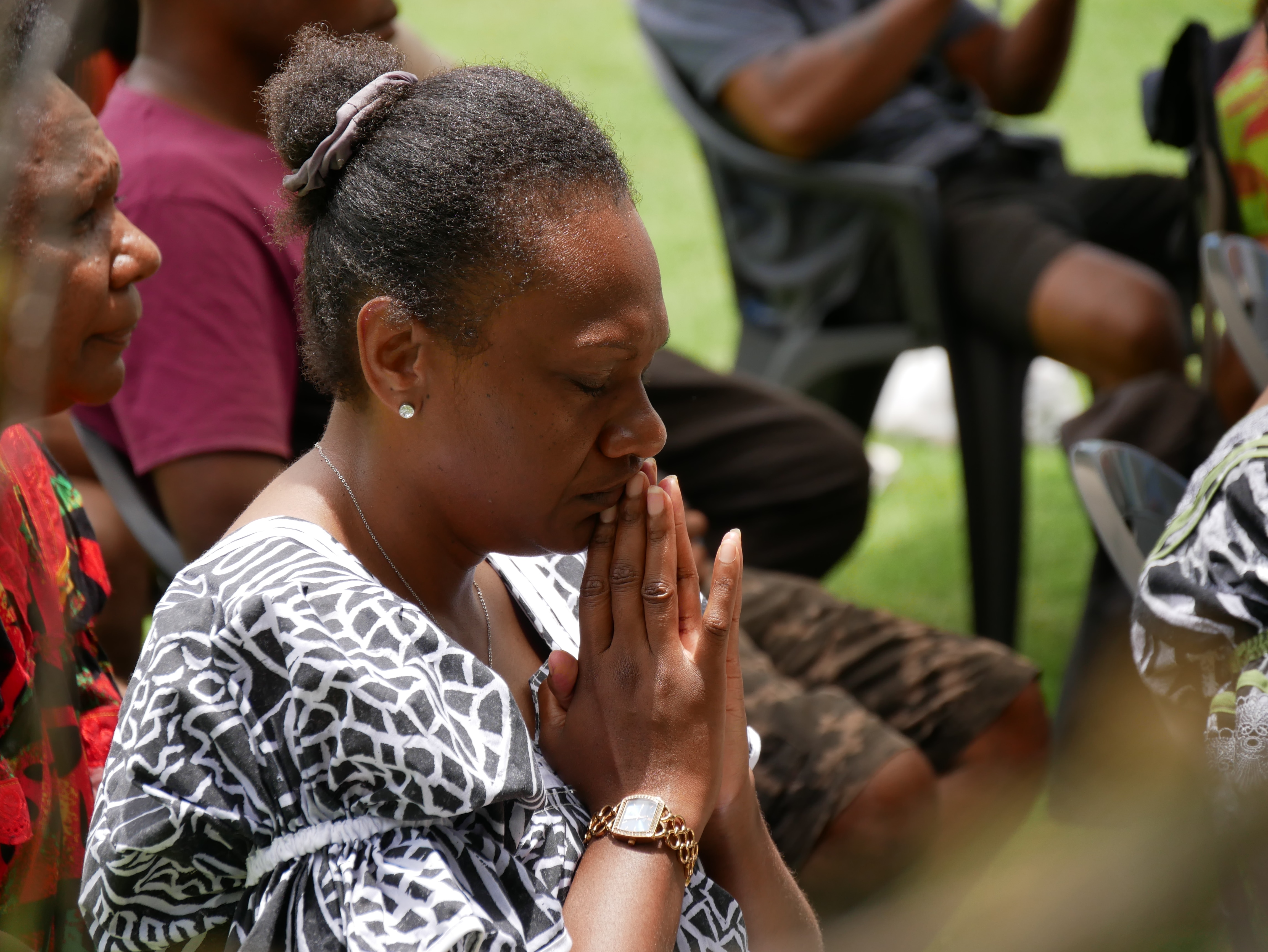 Una mujer de Vanuatu junta las manos e inclina la cabeza en oración.