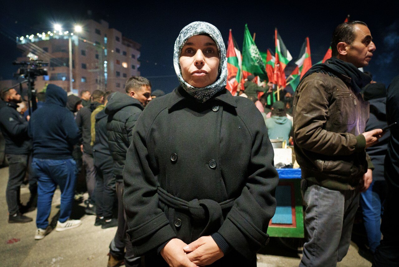 A woman standing outdoors at night and looking at the camera.