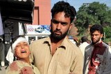 A Pakistani man carries an injured blast victim to a hospital in Peshawar