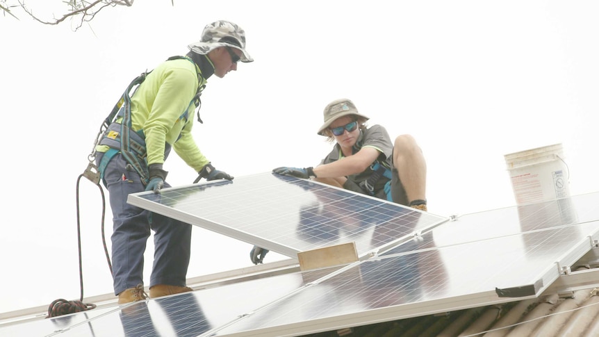 Two men working with solar panels on roof in Broome