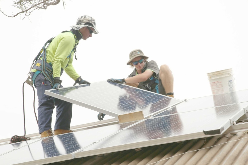 Two men working with solar panels on roof in Broome