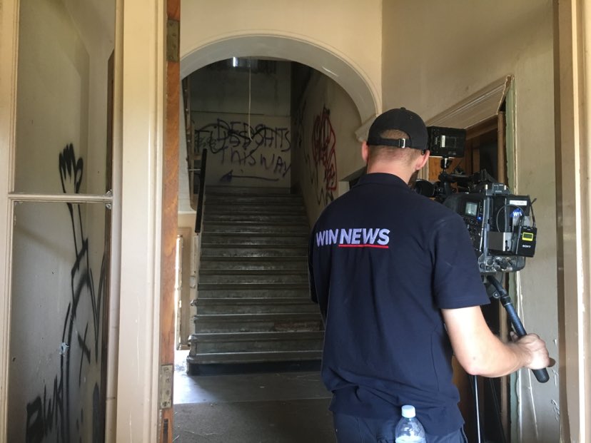 A cameraman filming inside a dilapidated house.