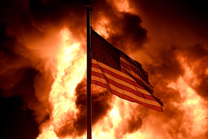 Flames engulf the Community Corrections Division building as an American flag flutters on a pole in Kenosha.