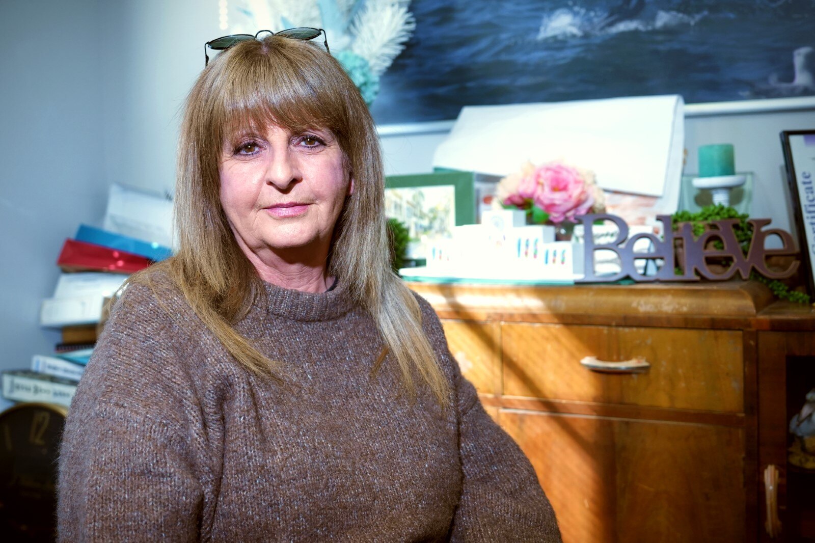 A woman in a brown jumper with blonde hair. 