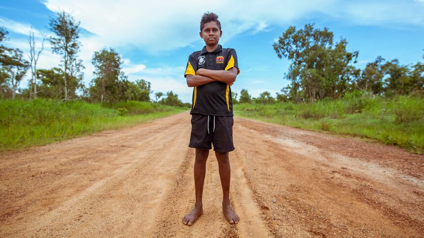 Junior Dirdi stands in middle of red dirt road