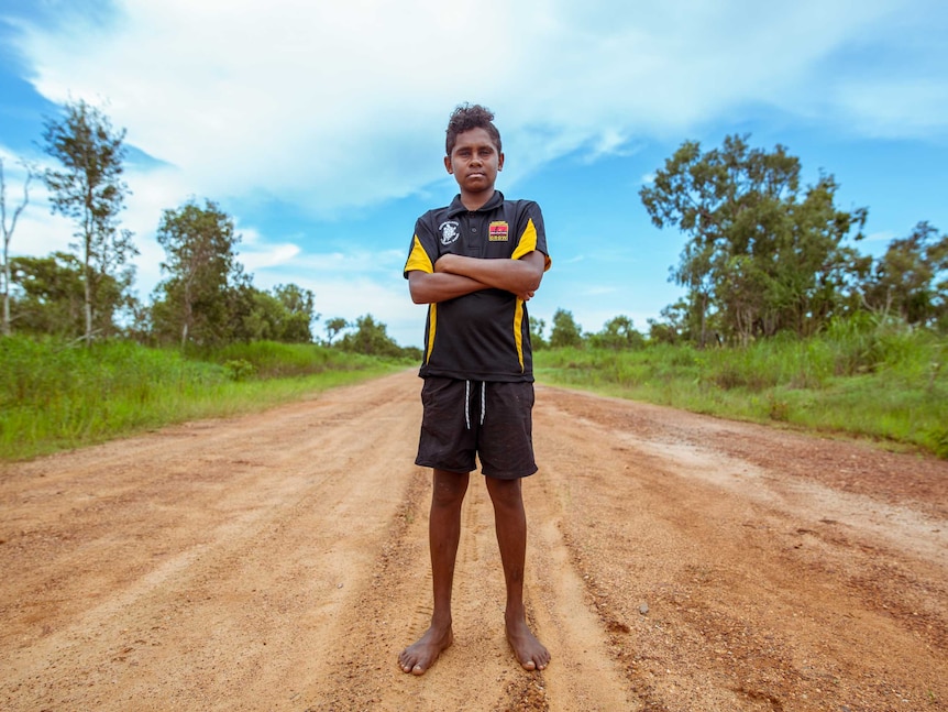 Junior Dirdi stands in middle of red dirt road