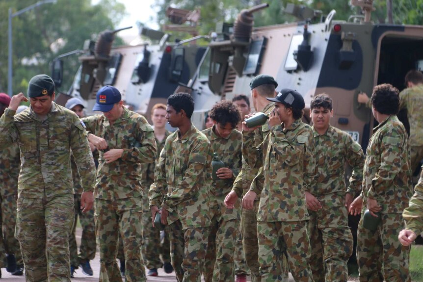 Indigenous teens gather around a tank at a military work experience day