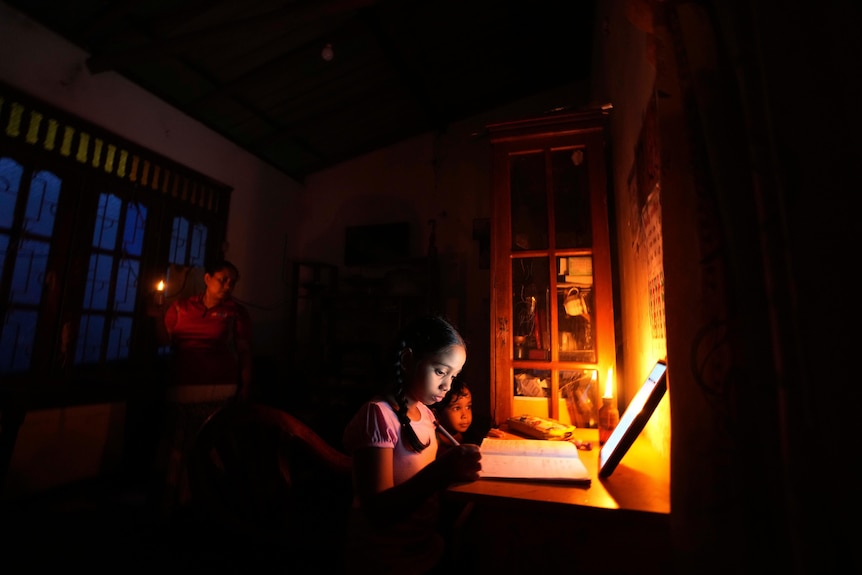 A girl uses a kerosine oil lamp to attend online lessons during a power cut in Colombo.