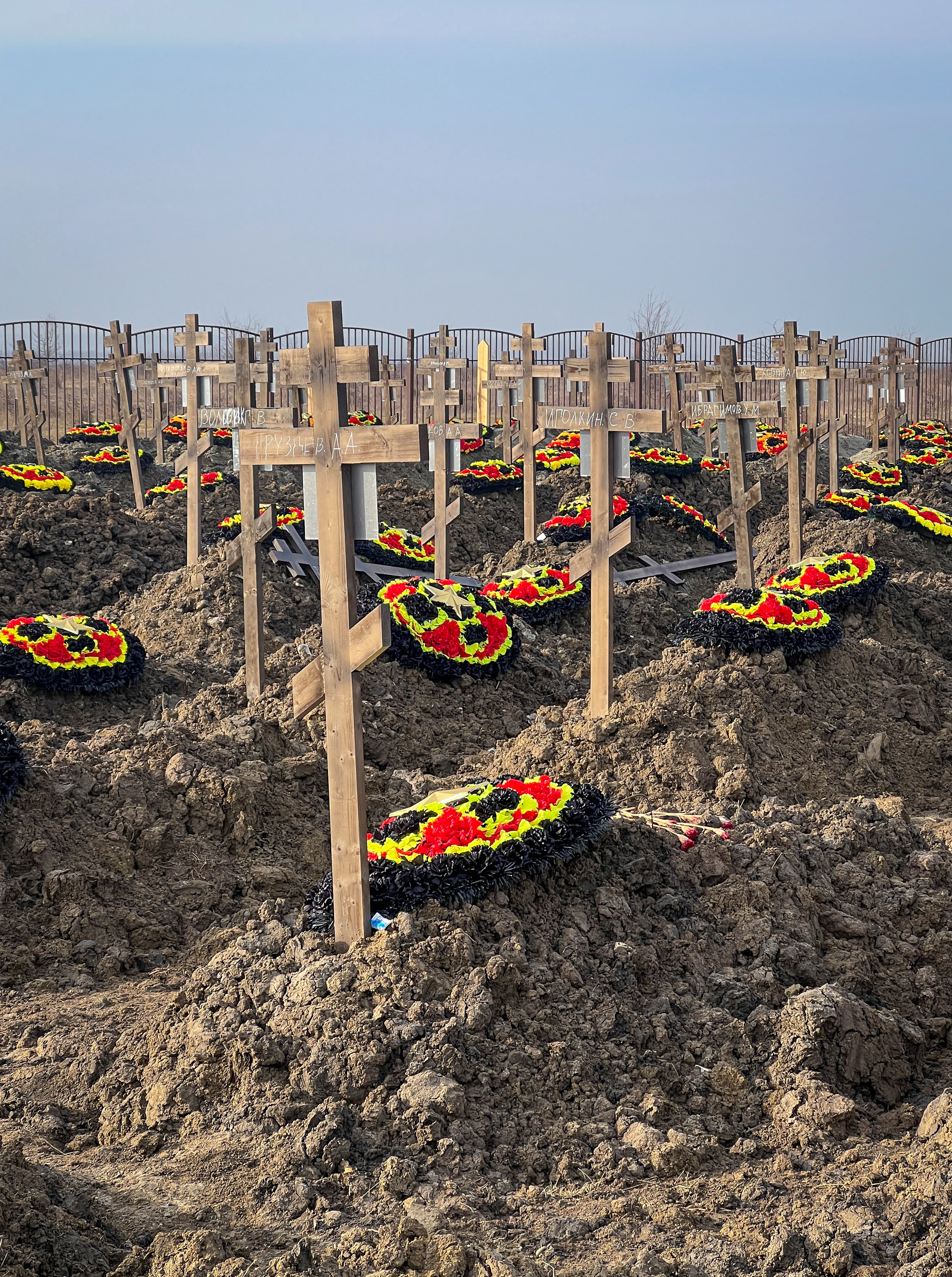 红黑黄相间的花环坐在土坟上，木十字架下一直延伸到地平线。 