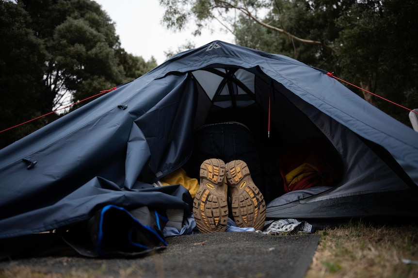 A person lies in a tent with only their feet sticking out. 