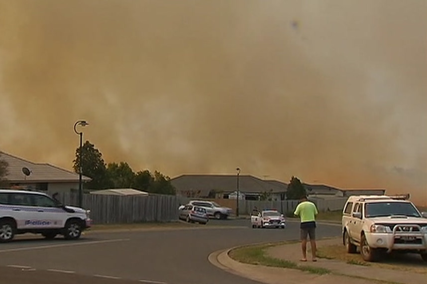 Smoke in the air over a suburban street at Bundamba, a number of police cars can be seen.