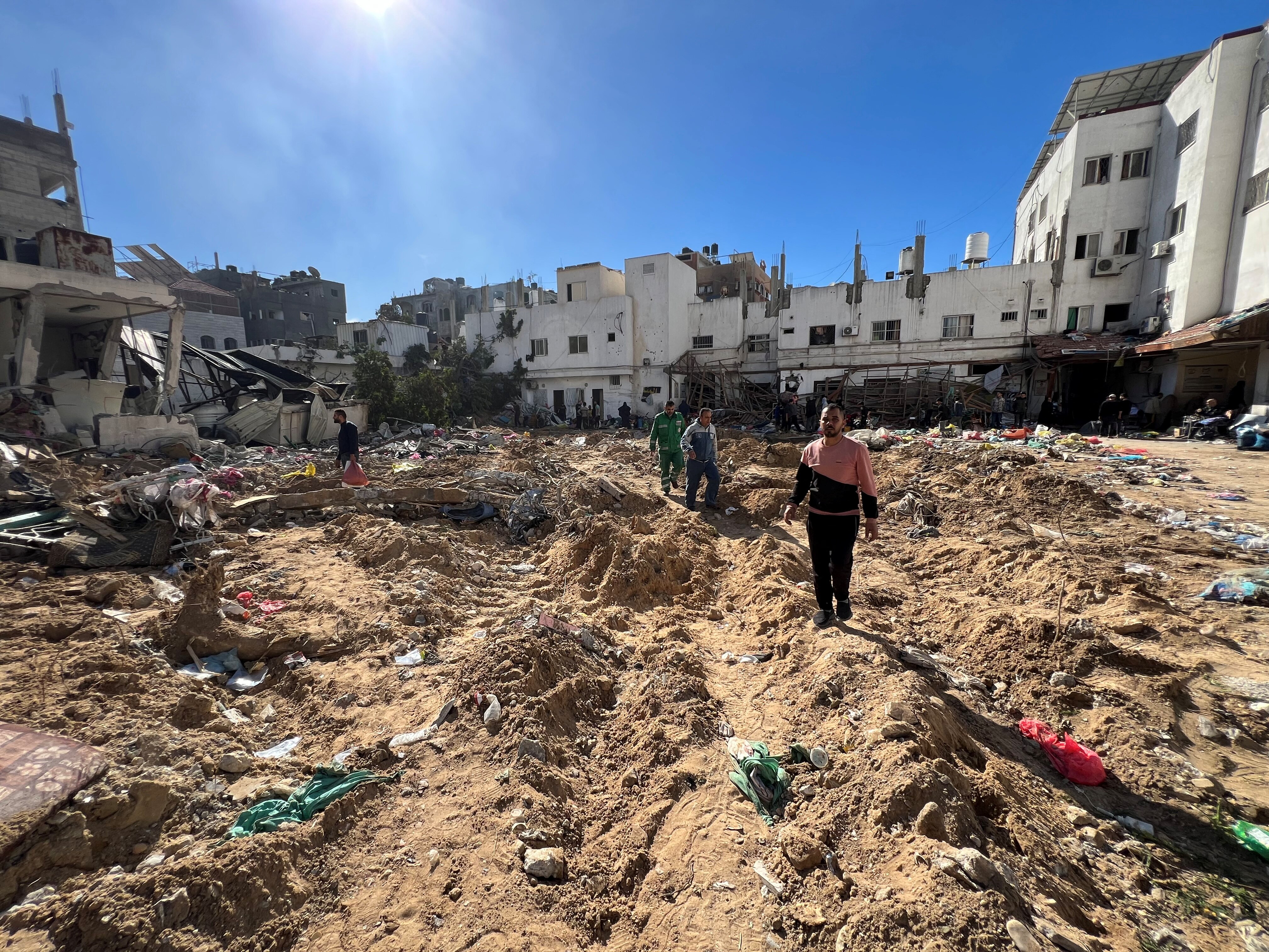People walk through the rubble of a building 