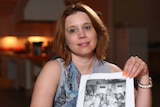 Joanna Hammond holds a black and white photo of a group of children.
