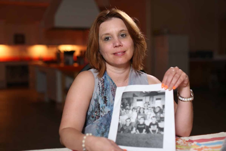 Joanna Hammond holds a black and white photo of a group of children.