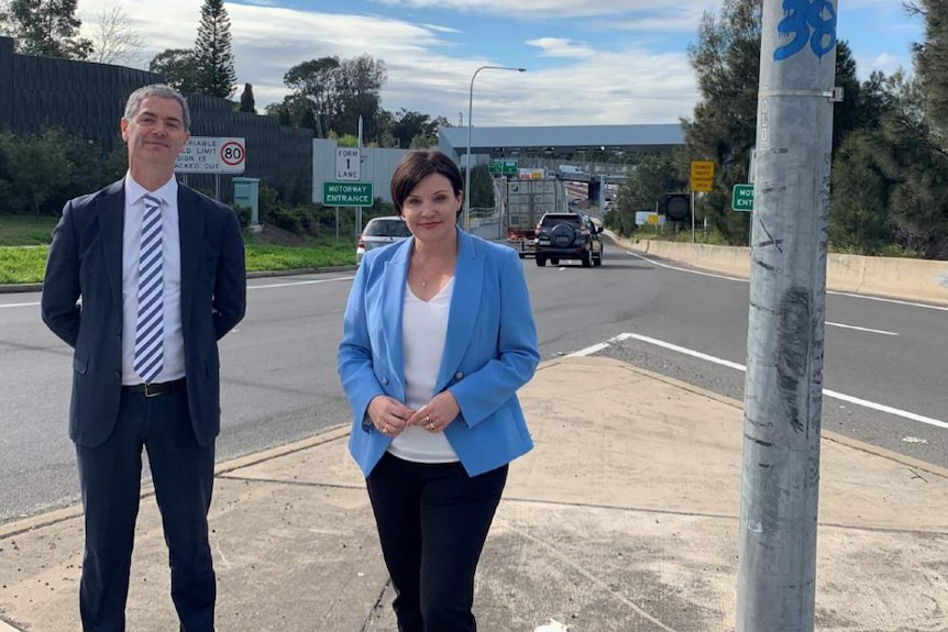 Two people stand by side of the road