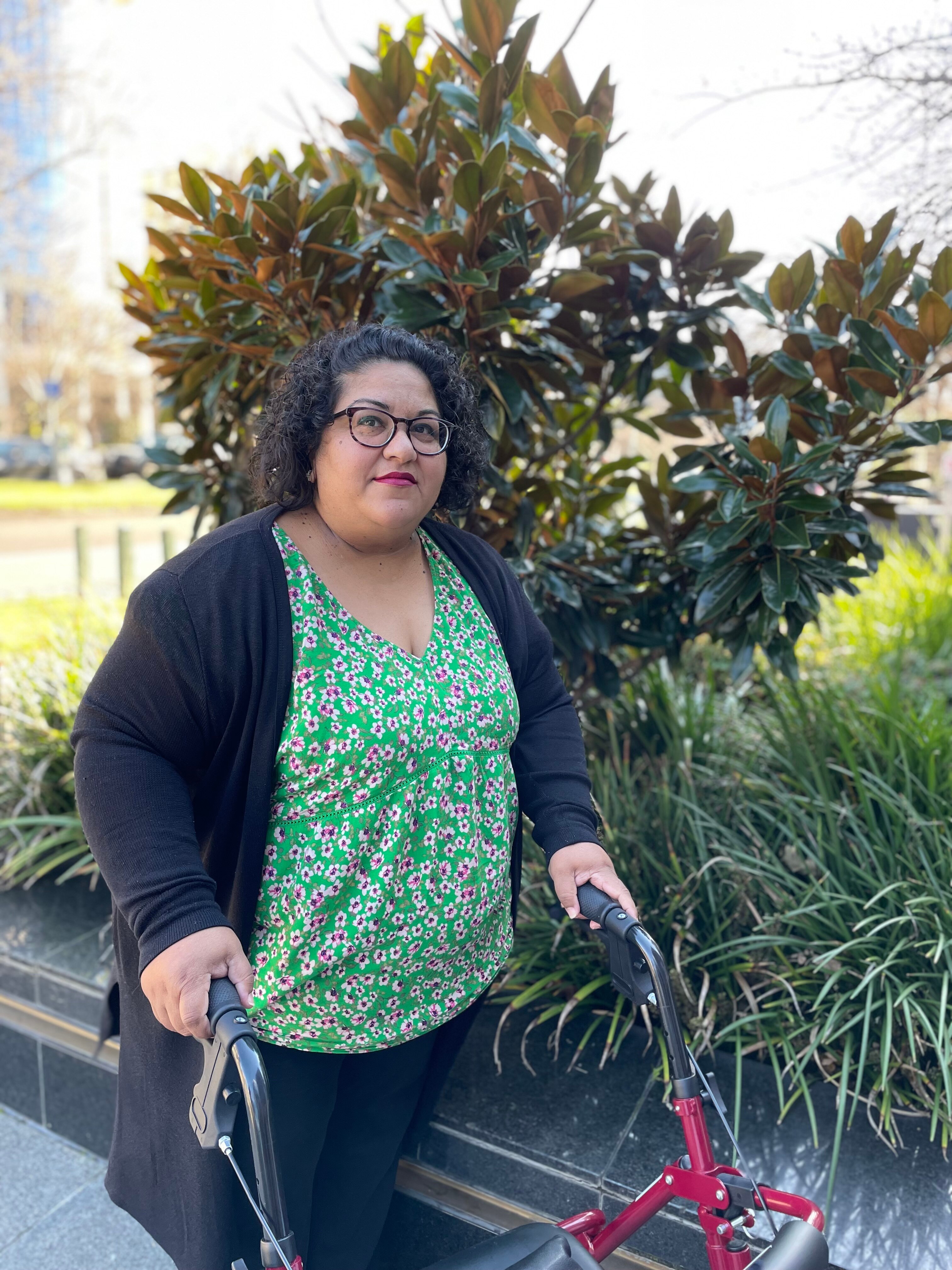 Long covid sufferer Sherene Magana-Cruz standing with walker side on not smiling 