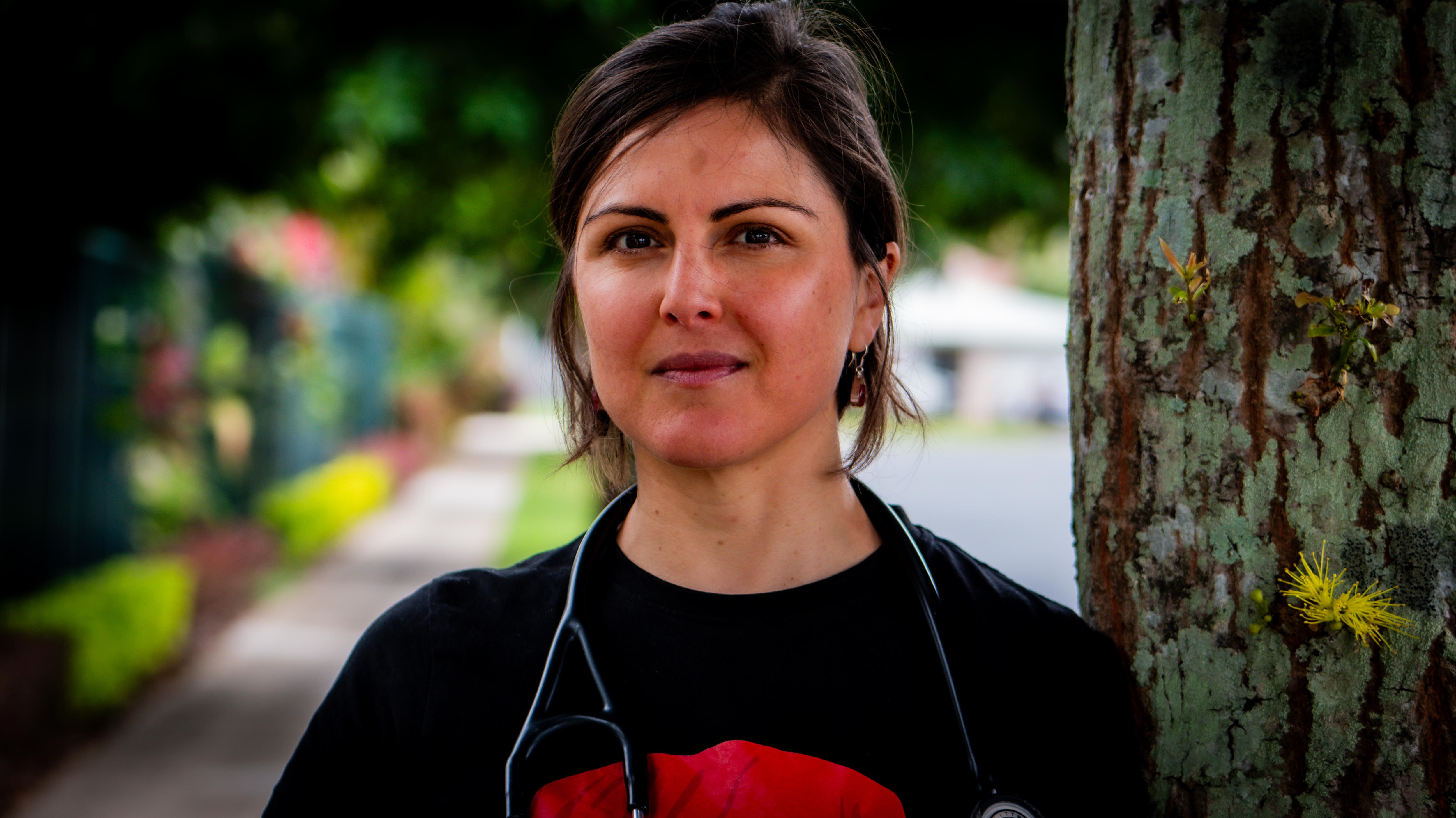 A woman with a stethoscope standing next to a tree