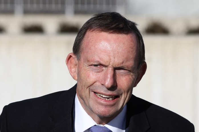 Tony Abbott arrives at Federal Parliament with bark blue suit, a white shirt, a like blue tie and a strained facial expression.