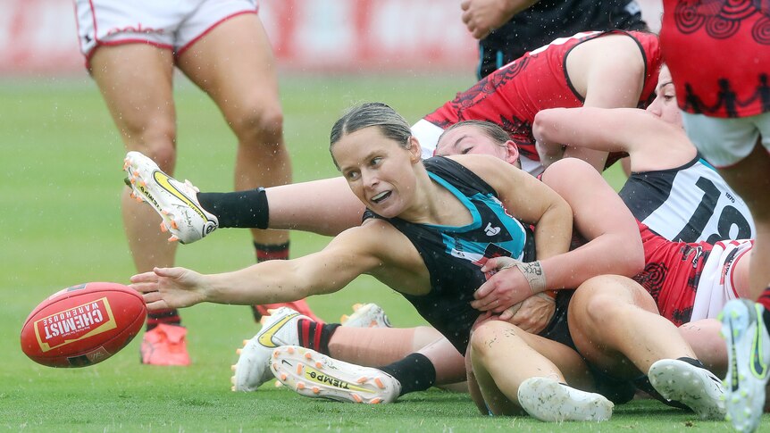 Kate Surman reaches for the football amongst a pack of Port Adelaide and Essendon players
