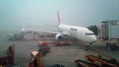 A Qantas plane at the airport terminal in fog (file)