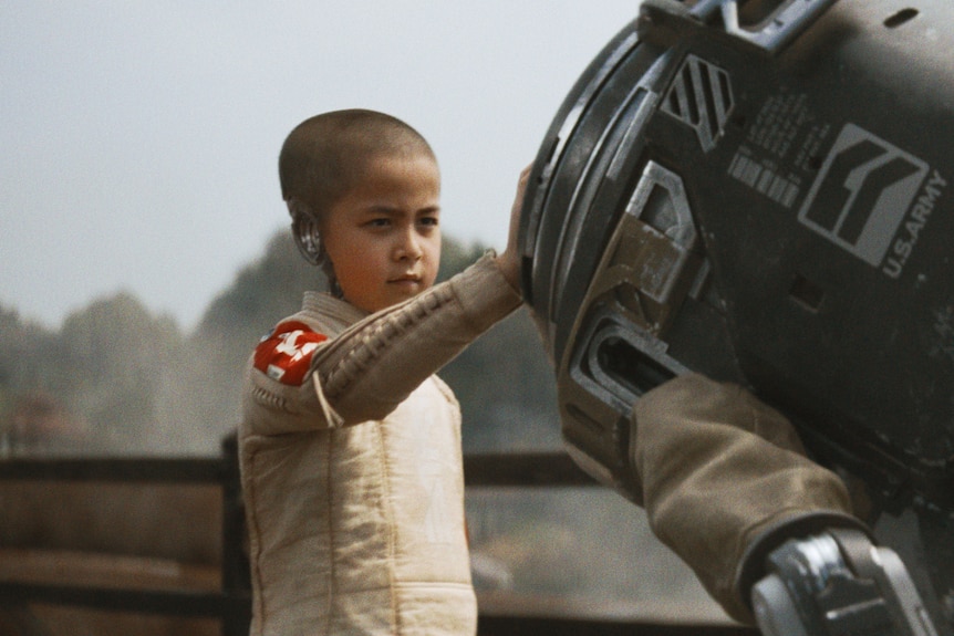 Young child rests their hand on a robot